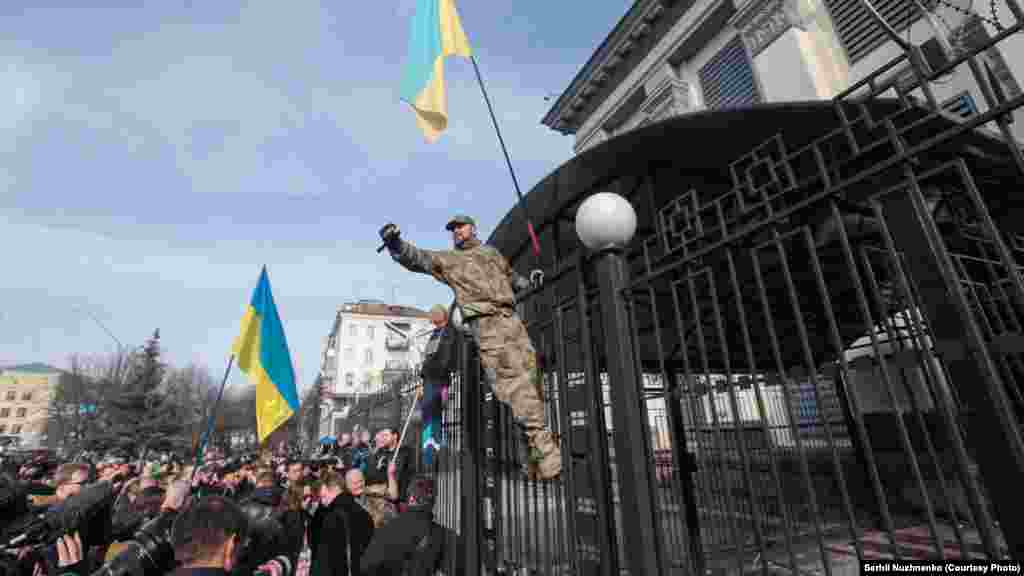 Спачатку актывісты закідалі будынак яйкамі і зялёнкай. Пазьней двое хлопцаў перабраліся праз плот.